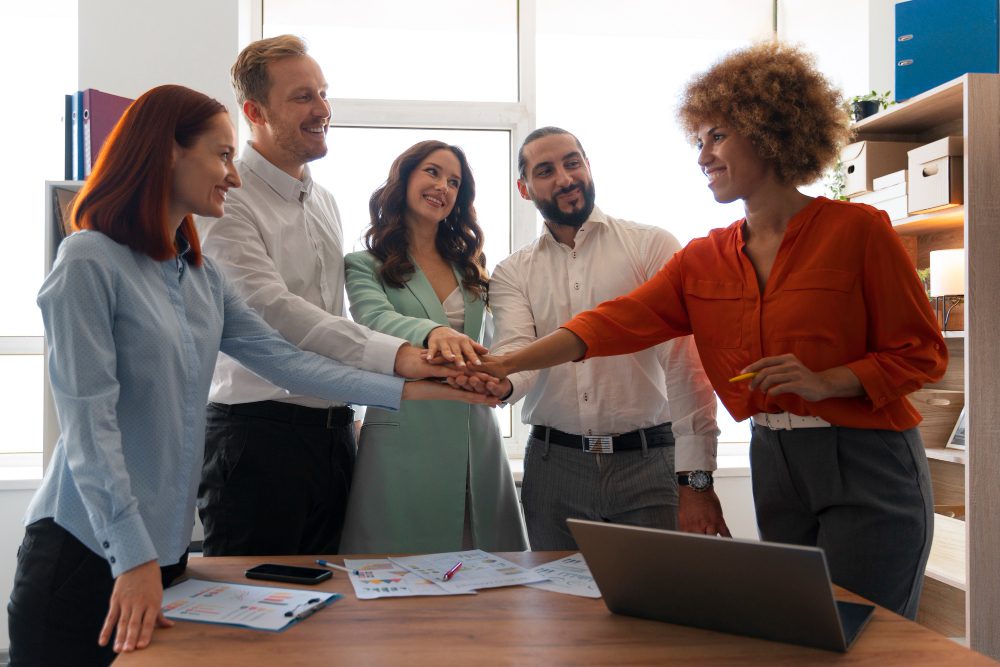 Diverse group of professionals standing in a circle, holding hands in a team gesture.